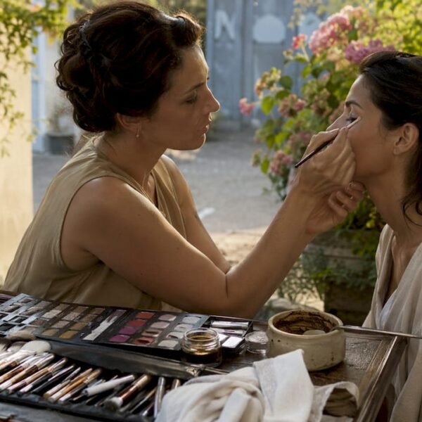 Una make-up artist esperta realizza un trucco correttivo su una modella, valorizzandone i lineamenti.