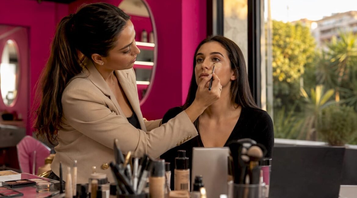 Una make-up artist stende il correttore sul viso durante una sessione in studio.