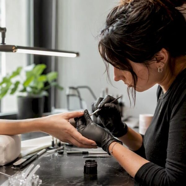 Una professionista sta applicando il gel sulle unghie di una cliente nel suo studio.